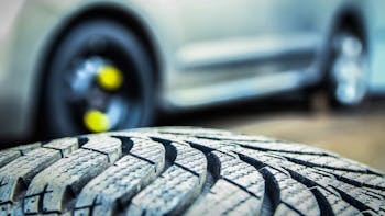 Close up on tire with car in background