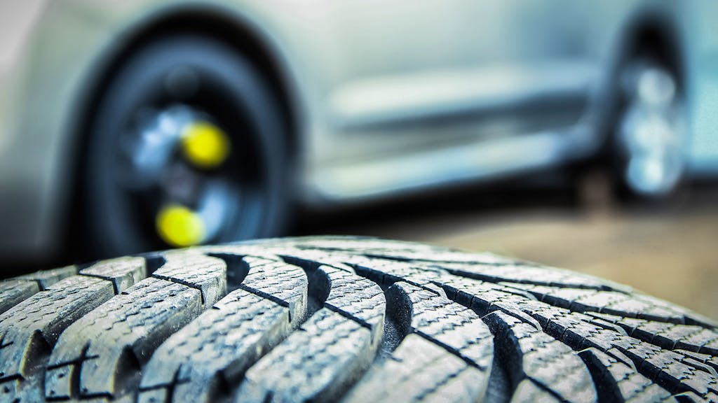 Close up on tire with car in background