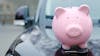 Piggy bank above hood of the car
