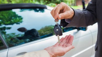 Close up on business man giving car keys to the buyer