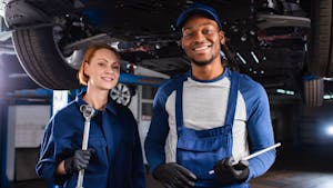 Positive multiethnic mechanics holding wrench and digital tablet