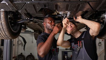 Two interracial diverse mechanics checking car bottom
