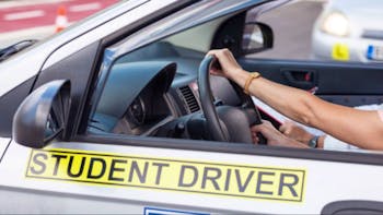 Middle-aged woman learning to drive a car with a driving instructor